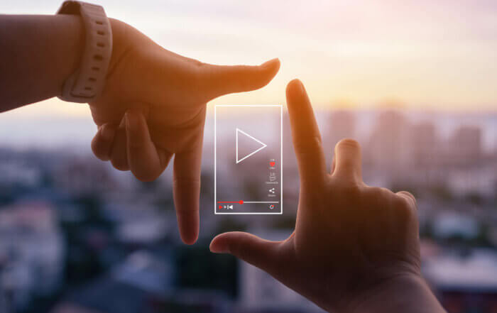 Hands outlining a social media video silhouette with a city in the background